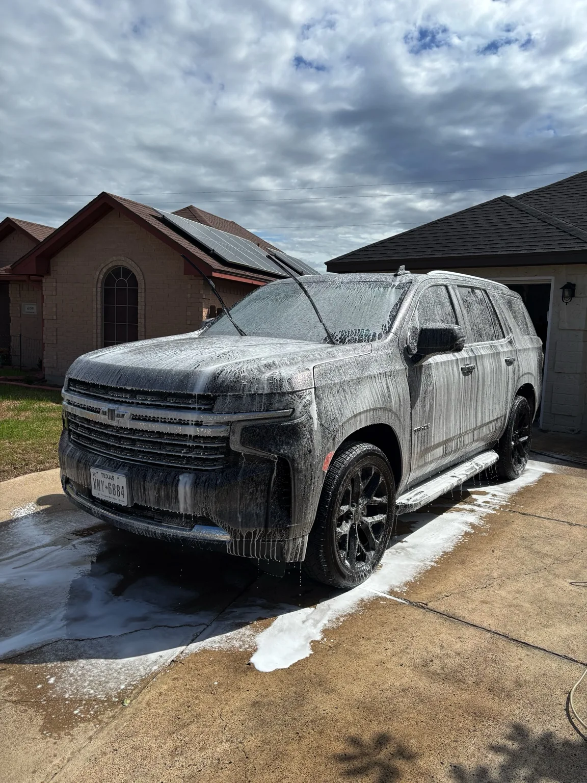Same black Chevrolet Tahoe covered in foam during its detail